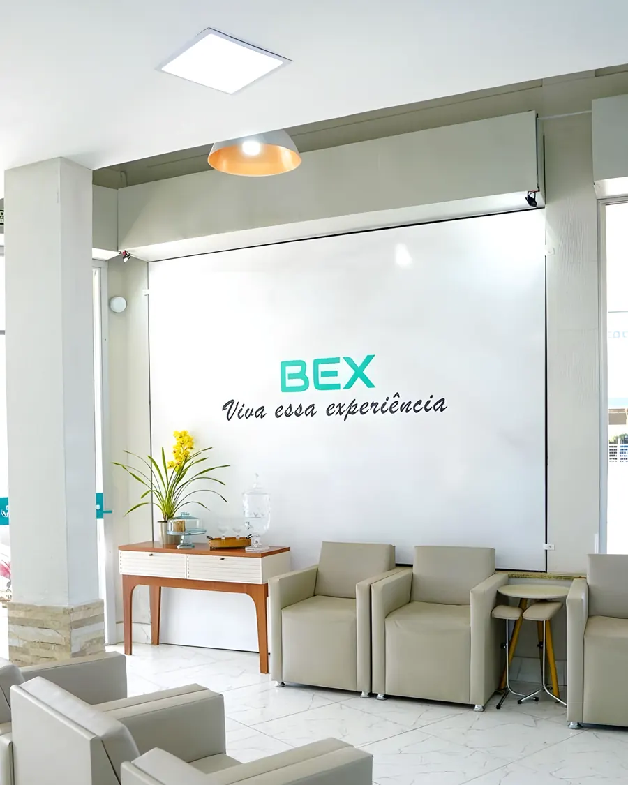 Recepção da BEX com a parede "BEX — Viva essa experiência" e poltronas claras